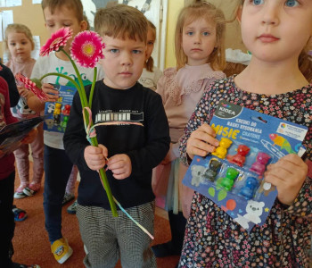chłopiec i dziewczynka trzymają kwiaty i prezenty